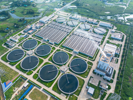 Aerial view of the Dhaka WASA Sewage Treatment Plant with circular settling tanks and industrial infrastructure surrounded by green fields in Dhaka Dhaka Division Bangladesh. Aerial view of the Dhaka WASA Sewage Treatment Plant with circular settling tanks and industrial infrastructure surrounded by green fields in Dhaka Dhaka Division Bangladesh.
