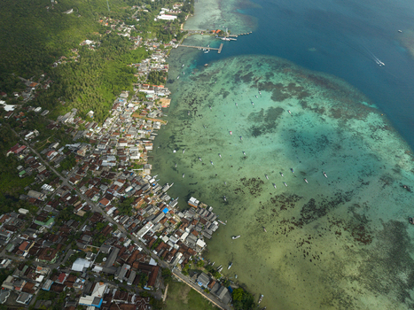 Aerial view of the contrasting vivid blues and greens of the ocean meeting the dense settlement by the shore Karimunjawa Central Java Indonesia. Aerial view of the contrasting vivid blues and greens of the ocean meeting the dense settlement by the shore Karimunjawa Central Java Indonesia.