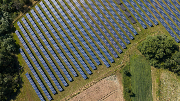 Aerial view of rows of solar panels installed in a rural field surrounded by trees in Atherstone England United Kingdom. Aerial view of rows of solar panels installed in a rural field surrounded by trees in Atherstone England United Kingdom.