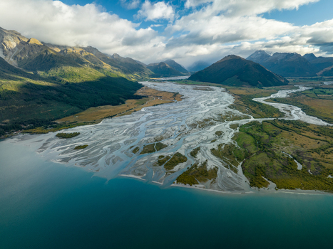 Aerial view of the braided Dart River flowing into Lake Wakatipu where turquoise waters meet rugged mountains under a sky streaked with clouds Glenorchy Otago Region New Zealand. Aerial view of the braided Dart River flowing into Lake Wakatipu where turquoise waters meet rugged mountains under a sky streaked with clouds Glenorchy Otago Region New Zealand.