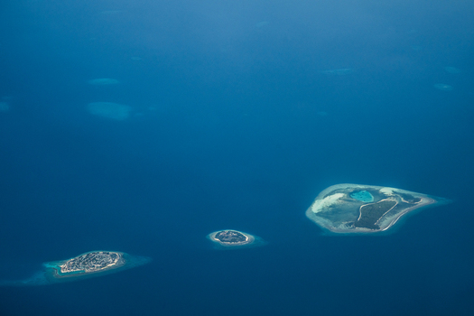 Aerial view of islands scattered like jewels in the vast deep blue ocean each fringed with white sand and vibrant turquoise shallows Flight from Male to Hanimaadhoo island Maldives.