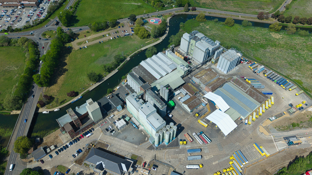 Aerial view of a large industrial milling complex with silos and warehouses situated next to a canal in Little Irchester England United Kingdom. Aerial view of a large industrial milling complex with silos and warehouses situated next to a canal in Little Irchester England United Kingdom.