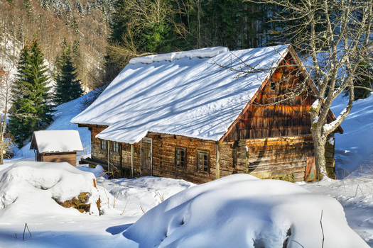 View of a rustic wooden cabin blanketed in fresh snow stands nestled among the winter trees a serene scene of tranquility Moce Banska Bystrica Region Slovakia.
