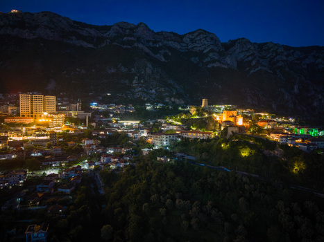 Aerial view of the illuminated Kruje Castle and the glowing city lights at the foot of the Skanderbeg Mountains at night in Kruje Durres County Albania.