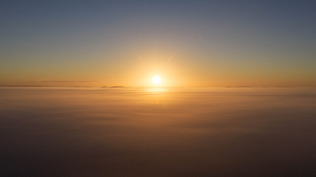 Aerial view of the sun rising above a thick layer of clouds at dawn creating a golden horizon over Salisbury England United Kingdom. Aerial view of the sun rising above a thick layer of clouds at dawn creating a golden horizon over Salisbury England United Kingdom.
