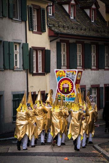 Basel Switzerland 10 March 2025 View of golden clad figures parade through the historic Fasnacht their pointed hats and costumes shimmering against the backdrop of traditional buildings. Basel Switzerland 10 March 2025 View of golden clad figures parade through the historic Fasnacht their pointed hats and costumes shimmering against the backdrop of traditional buildings.