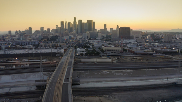 Aerial view of the Los Angeles skyline at sunset featuring a bridge in the foreground urban infrastructure and distant mountains in Los Angeles California United States. Aerial view of the Los Angeles skyline at sunset featuring a bridge in the foreground urban infrastructure and distant mountains in Los Angeles California United States.