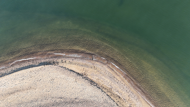 Aerial view of the curved sandy shoreline of Sandy Point State Park meeting the calm green waters of the Chesapeake Bay in Annapolis Maryland United States. Aerial view of the curved sandy shoreline of Sandy Point State Park meeting the calm green waters of the Chesapeake Bay in Annapolis Maryland United States.