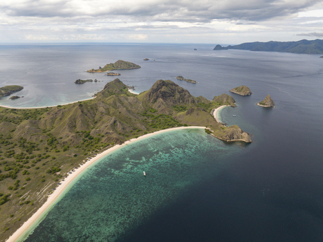 Aerial view of Pink Beach with turquoise waters coral reefs and green hills in East Nusa Tenggara Indonesia. Aerial view of Pink Beach with turquoise waters coral reefs and green hills in East Nusa Tenggara Indonesia.