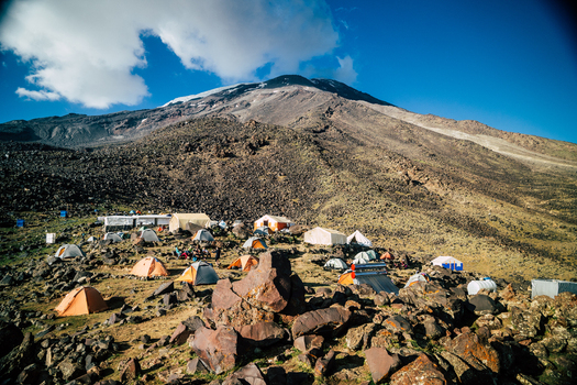 View of a base camp with colorful tents set up on the rocky slopes of Mount Ararat in Turkey.
