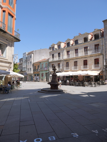 View of the historic Fonte da Praza de Curros Enriquez in a sunny square surrounded by traditional stone buildings with balconies and outdoor cafe seating in Pontevedra Pontevedra Spain. View of the historic Fonte da Praza de Curros Enriquez in a sunny square surrounded by traditional stone buildings with balconies and outdoor cafe seating in Pontevedra Pontevedra Spain.