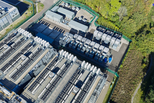 Aerial view of a data center with rows of cooling units and server infrastructure inside a secure fenced facility in the United Kingdom.