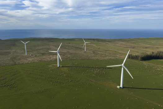 Aerial view of a windfarm with white turbines standing on green coastal fields under a blue sky in Scotland United Kingdom. Aerial view of a windfarm with white turbines standing on green coastal fields under a blue sky in Scotland United Kingdom.