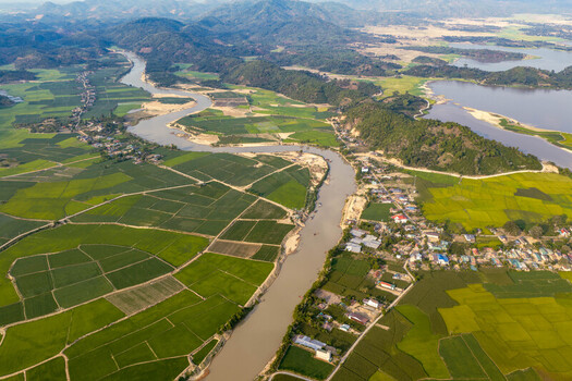 Aerial view of Lak Lake surrounded by lush green rice fields winding river and small village houses in Lien Son Lak Dak Lak Vietnam. Aerial view of Lak Lake surrounded by lush green rice fields winding river and small village houses in Lien Son Lak Dak Lak Vietnam.