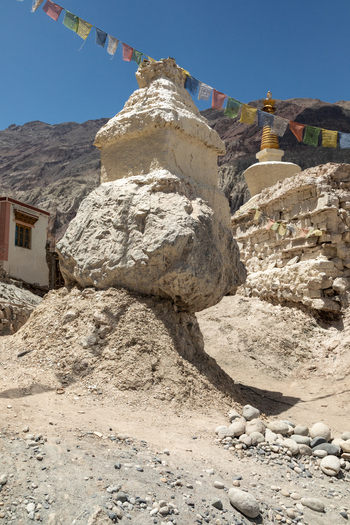 View of the ancient stone stupas at Charasa Gonpa adorned with colorful prayer flags under a clear blue sky in the rugged landscape of Charasa Ladakh India.