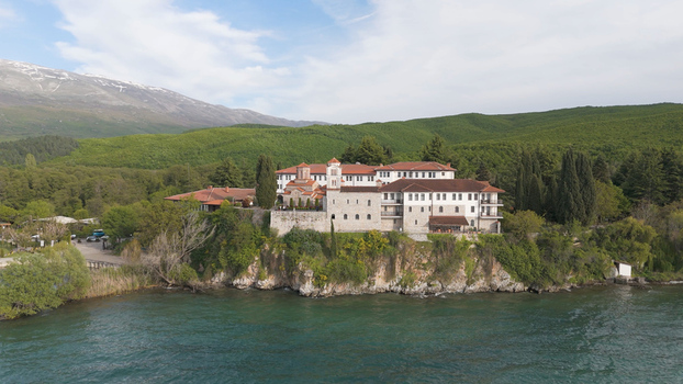 Aerial view of the historic Saint Naum Monastery situated on the rocky shore of Lake Ohrid surrounded by lush green hills and mountains in Municipality of Ohrid North Macedonia.