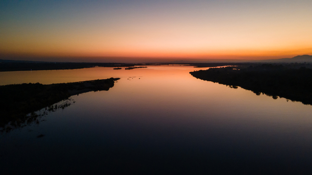 Aerial view of the Jhelum River with calm water reflecting the vibrant sunset sky and silhouetted banks Jhelum Punjab Pakistan. Aerial view of the Jhelum River with calm water reflecting the vibrant sunset sky and silhouetted banks Jhelum Punjab Pakistan.