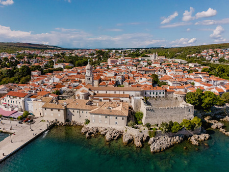 Aerial view of the historic town of Krk featuring Frankopan Castle and the cathedral surrounded by terracotta rooftops along the Adriatic coast in Krk Primorje Gorski Kotar Croatia.