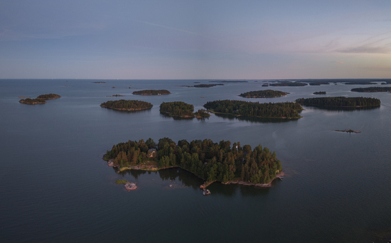 Aerial view of the Baltic Sea archipelago featuring small forested islands surrounded by calm waters under a soft evening sky in Espoo Uusimaa Finland. Aerial view of the Baltic Sea archipelago featuring small forested islands surrounded by calm waters under a soft evening sky in Espoo Uusimaa Finland.