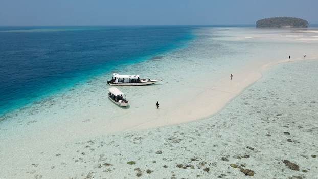 Aerial view of Raja Ampat featuring turquoise waters white sandbars and small boats with people walking on the beach in Raja Ampat Southwest Papua Indonesia. Aerial view of Raja Ampat featuring turquoise waters white sandbars and small boats with people walking on the beach in Raja Ampat Southwest Papua Indonesia.