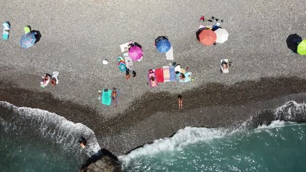 Aerial view of people sunbathing on a pebble beach in Imperia Italy. Aerial view of people sunbathing on a pebble beach in Imperia Italy.