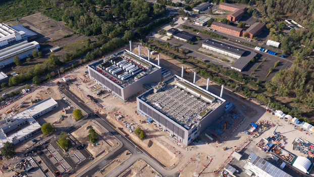 Aerial view of the Data4 Hanau data center featuring large industrial buildings with rooftop cooling units surrounded by construction zones access roads and forest in Hanau Hessen Germany. Aerial view of the Data4 Hanau data center featuring large industrial buildings with rooftop cooling units surrounded by construction zones access roads and forest in Hanau Hessen Germany.