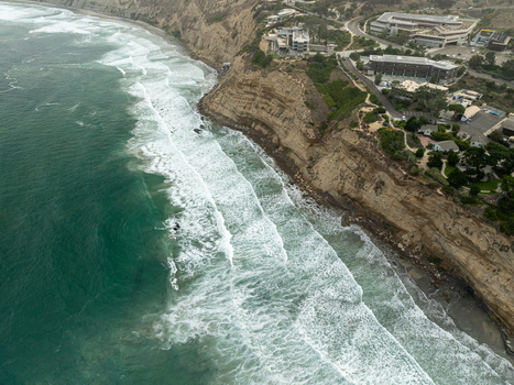 Aerial view of La Jolla Cove with steep coastal cliffs crashing ocean waves and modern buildings along the shoreline San Diego California United States. Aerial view of La Jolla Cove with steep coastal cliffs crashing ocean waves and modern buildings along the shoreline San Diego California United States.