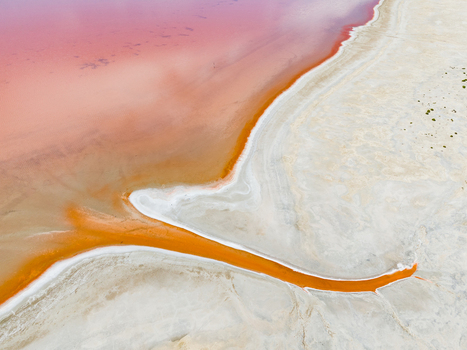 Aerial view of a vibrant pink salt lake with striking orange mineral deposits and white salt crusts in the Mallee region Woorinen North Victoria Australia. Aerial view of a vibrant pink salt lake with striking orange mineral deposits and white salt crusts in the Mallee region Woorinen North Victoria Australia.