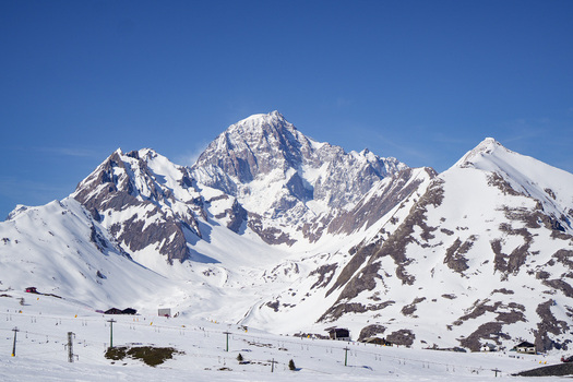 Aerial view of the snow covered peaks of the Mont Blanc massif and ski slopes with lift infrastructure under a clear blue sky in La Thuile Valle d Aosta Italy. Aerial view of the snow covered peaks of the Mont Blanc massif and ski slopes with lift infrastructure under a clear blue sky in La Thuile Valle d Aosta Italy.