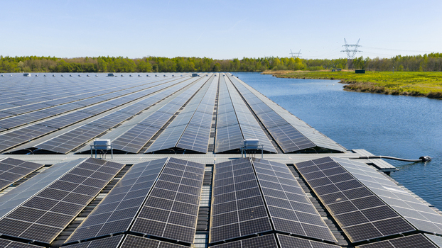 Aerial view of floating solar panels on a calm lake surrounded by lush green forests and power lines under a clear sky Zwolle Overijssel Netherlands. Aerial view of floating solar panels on a calm lake surrounded by lush green forests and power lines under a clear sky Zwolle Overijssel Netherlands.