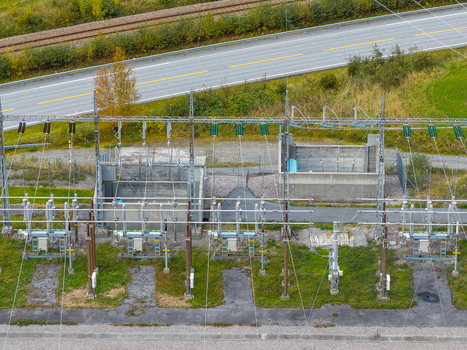 Aerial view of an electrical substation with power lines transformers and concrete structures located near a road and railway in Andalsnes More og Romsdal Norway. Aerial view of an electrical substation with power lines transformers and concrete structures located near a road and railway in Andalsnes More og Romsdal Norway.