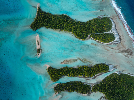 Aerial view of lush green motus surrounded by turquoise lagoon waters and coral reefs in Moorea Maiao Windward Islands French Polynesia. Aerial view of lush green motus surrounded by turquoise lagoon waters and coral reefs in Moorea Maiao Windward Islands French Polynesia.
