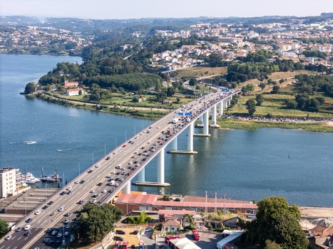 Aerial view of Ponte do Infante bridge spanning the Douro River with heavy traffic surrounded by lush green hills and urban development in Vila Nova de Gaia Porto Portugal.