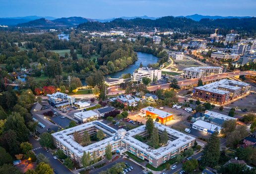 Aerial view of the Willamette River winding through the urban landscape of Eugene featuring modern buildings trees and city streets at dusk in Eugene Oregon United States. Aerial view of the Willamette River winding through the urban landscape of Eugene featuring modern buildings trees and city streets at dusk in Eugene Oregon United States.