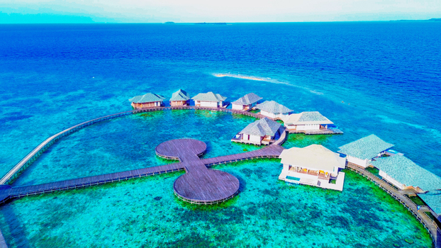 Aerial view of overwater bungalows connected by wooden walkways over turquoise coral reef waters in Karimun Jawa Jepara Central Java Indonesia. Aerial view of overwater bungalows connected by wooden walkways over turquoise coral reef waters in Karimun Jawa Jepara Central Java Indonesia.