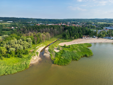 Aerial view of a stream flowing into the Vistula Lagoon with a sandy beach lush forest and the town in the background Tolkmicko Warmian Masurian Voiv Poland. Aerial view of a stream flowing into the Vistula Lagoon with a sandy beach lush forest and the town in the background Tolkmicko Warmian Masurian Voiv Poland.