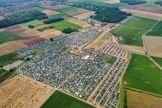 Herzogenaurach Germany 26 July 2025 Aerial view of Open Beatz Festival featuring a large campsite with tents a Ferris wheel and parking areas surrounded by green fields.