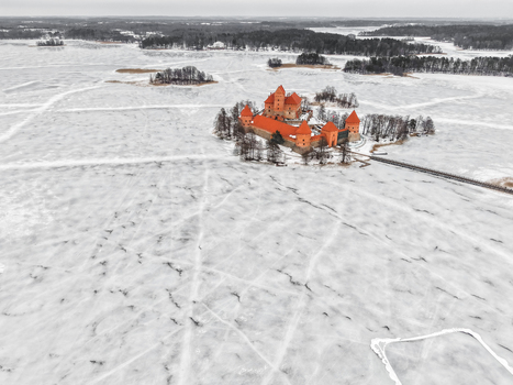 Aerial view of Trakai Island Castle surrounded by a vast frozen lake with snow covered landscape and bare trees in winter in Trakai Vilnius County Lithuania. Aerial view of Trakai Island Castle surrounded by a vast frozen lake with snow covered landscape and bare trees in winter in Trakai Vilnius County Lithuania.