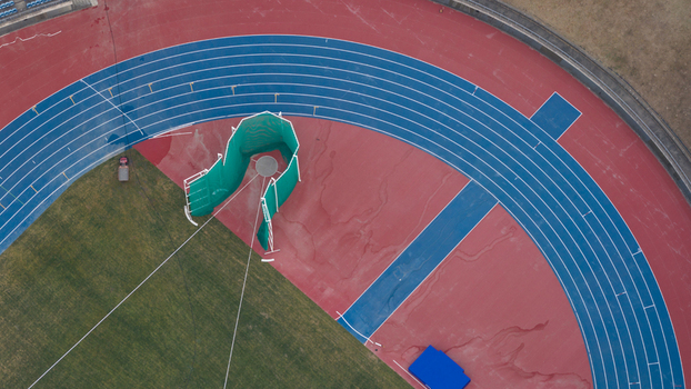 Aerial view of Kaohsiung National Stadium featuring the blue running track lanes and green throwing cage on the field Juguang Village Kaohsiung City Taiwan.