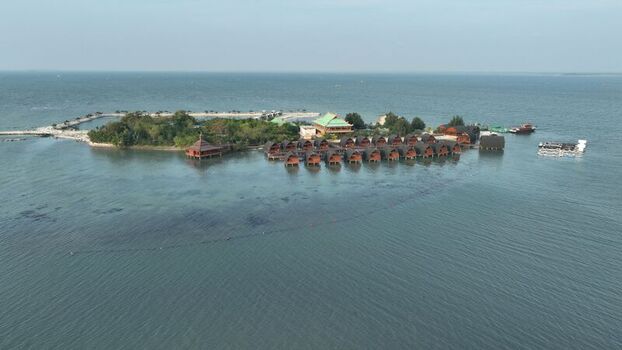 Aerial view of Pulau Lima Resort featuring wooden overwater bungalows lush greenery and clear turquoise waters in Kasemen Banten Indonesia. Aerial view of Pulau Lima Resort featuring wooden overwater bungalows lush greenery and clear turquoise waters in Kasemen Banten Indonesia.