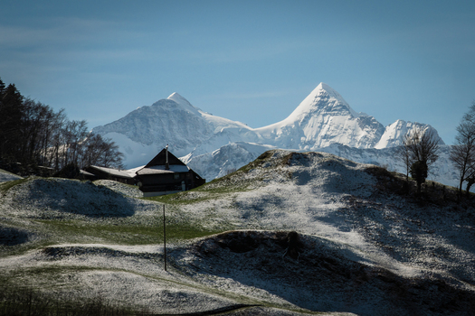 View of a rustic wooden house nestled in a snow dusted landscape with majestic snow capped mountains piercing the clear blue sky Train from Lucerne Switzerland. View of a rustic wooden house nestled in a snow dusted landscape with majestic snow capped mountains piercing the clear blue sky Train from Lucerne Switzerland.