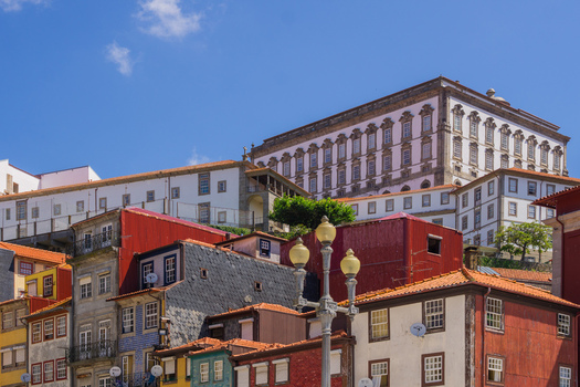 View of terracotta roofs cascading down the hillside beneath a grand white building under a clear blue sky Porto Porto District Portugal. View of terracotta roofs cascading down the hillside beneath a grand white building under a clear blue sky Porto Porto District Portugal.