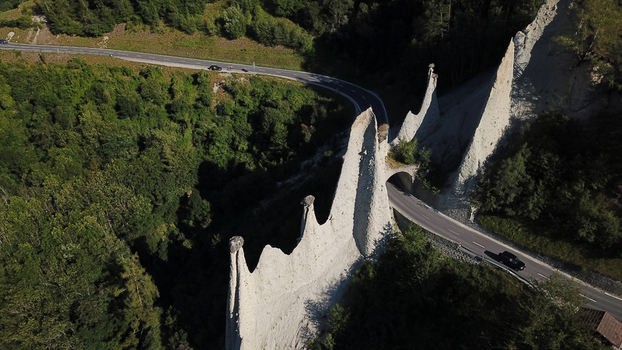 Aerial view of Pyramides d Euseigne unique earth pyramids with a road tunnel passing through them surrounded by lush green forest Heremence Valais Switzerland. Aerial view of Pyramides d Euseigne unique earth pyramids with a road tunnel passing through them surrounded by lush green forest Heremence Valais Switzerland.