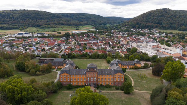 Aerial view of Schloss Lowenstein surrounded by lush gardens and the town of Kleinheubach with its historic rooftops under a cloudy sky in Kleinheubach Bayern Germany. Aerial view of Schloss Lowenstein surrounded by lush gardens and the town of Kleinheubach with its historic rooftops under a cloudy sky in Kleinheubach Bayern Germany.