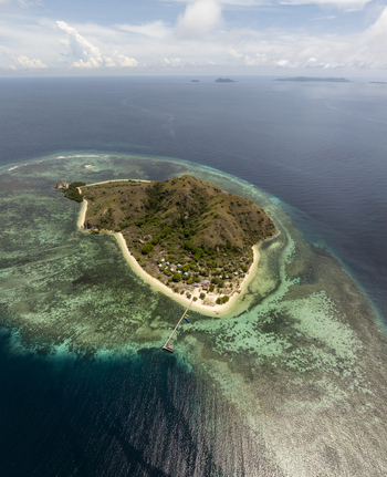 Aerial view of Kanawa Island with its lush green hills white sandy beach wooden jetty and surrounding turquoise coral reefs in Kecamatan Komodo Nusa Tenggara Timur Indonesia. Aerial view of Kanawa Island with its lush green hills white sandy beach wooden jetty and surrounding turquoise coral reefs in Kecamatan Komodo Nusa Tenggara Timur Indonesia.