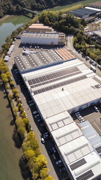 Aerial view of an industrial warehouse complex with solar panels on the roof situated along a riverbank in Zumaia Basque Country Spain.