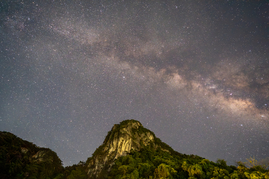 View of the Milky Way galaxy shining brightly over a rugged vegetation covered mountain peak in Vietnam. View of the Milky Way galaxy shining brightly over a rugged vegetation covered mountain peak in Vietnam.