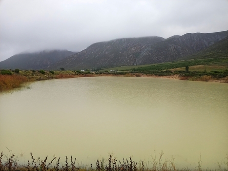 View of a calm lake in the Klein Karoo region with rugged mountains under a cloudy sky in Robertson Western Cape South Africa. View of a calm lake in the Klein Karoo region with rugged mountains under a cloudy sky in Robertson Western Cape South Africa.