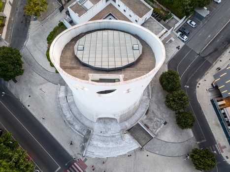 Alges Portugal 25 July 2026 Aerial view of the Santissima Trindade Church a distinctive modern circular structure with a glass roof surrounded by paved plazas trees and urban streets.