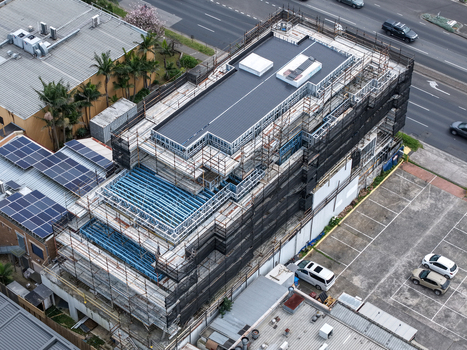 Melbourne Australia 25 September 2026 Aerial view of a building under construction featuring extensive scaffolding steel framing and protective netting in an urban setting.